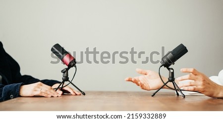 Two women in local broadcat studio recording audio podcast. Sitting opposite each other, hands close-up