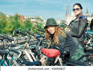 Two women locking their bikes at big cycling parking in Amsterdam, Dutch capital