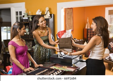 Two women making purchase  from sales clerk in boutique. - Powered by Shutterstock