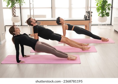 Two women and a man are doing yoga in the studio. - Shutterstock ID 2368781195