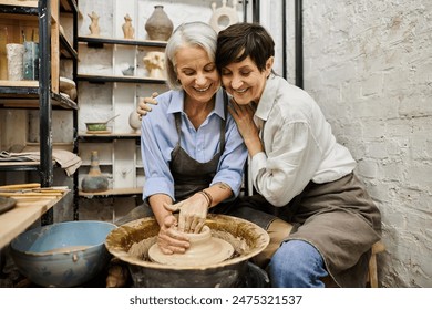 Two women, a mature lesbian couple, work together at a pottery wheel in a cozy art studio. - Powered by Shutterstock