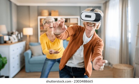 two women mature senior caucasian female friends or sisters at home enjoy virtual reality VR headset real people active senior having fun leisure concept - Powered by Shutterstock