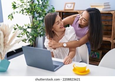 Two Women Mother And Daughter Hugging Each Other Using Laptop At Home