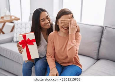 Two women mother and daughter surprise with gift at home - Powered by Shutterstock