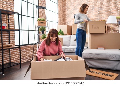 Two women mother and daughter unpacking cardboard box at new home - Powered by Shutterstock