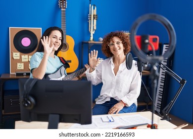 Two Women Musicians Having Online Electrical Guitar Lesson By Smartphone At Music Studio