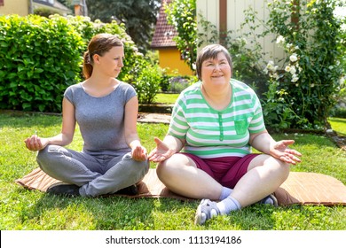 two women, one of them a fitness or yoga coach, are doing some yoga or relaxation exercises, on woman is mentally disabled