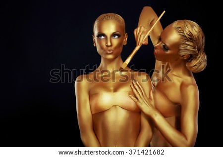 Two women painted in gold paint.