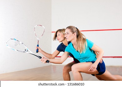 Two women playing squash as racket sport in gym, it might be a competition