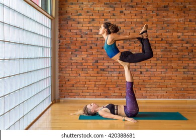 Two Women Practice Acroyoga, Showing Friendship, Trust And Strengh.