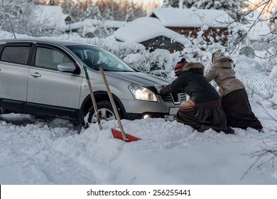 Two Women Pushing A Car Stuck In The Snow