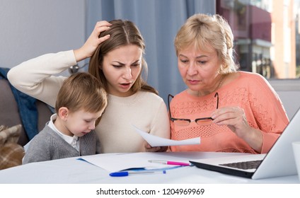 Two women are puzzled of problems with filling utility bills with laptop at home.