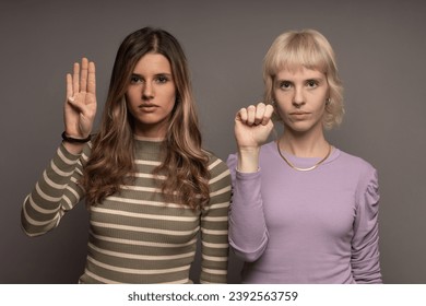 Two women raising hands in a silent plea, showcasing the SOS sign against domestic violence, promoting awareness and support. - Powered by Shutterstock