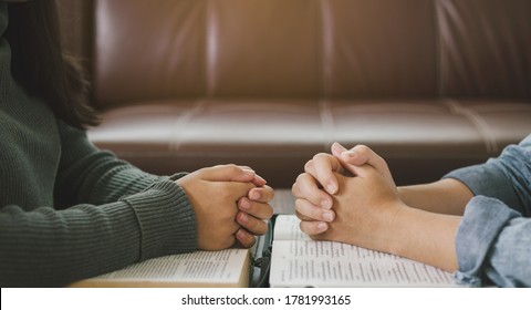 zwei Frauen, die zu Hause Bibel lesen und studieren und zusammen beten.
