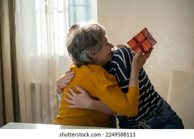 Two women, relatives, happily spend time together, grandmother and daughter give gifts to each other for the holidays, make pleasant surprises, love and emotional bonding inside the family. - Powered by Shutterstock