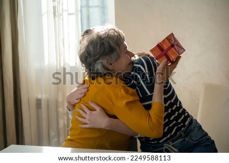 Two women, relatives, happily spend time together, grandmother and daughter give gifts to each other for the holidays, make pleasant surprises, love and emotional bonding inside the family.
