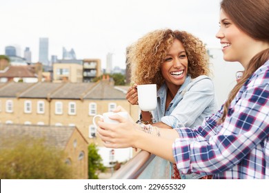 Two Women Relaxing On Rooftop Garden Drinking Coffee