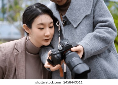 Two Women Reviewing Images on DSLR Camera Outdoors - Powered by Shutterstock