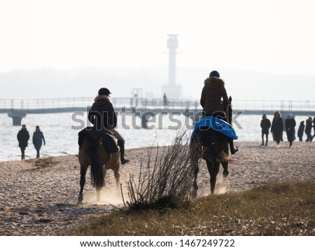 Two women riding on horses at the beach