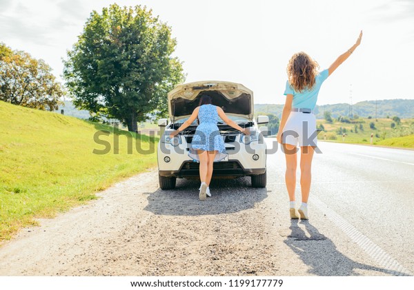 two women at roadside need help with broken car.\
car travel