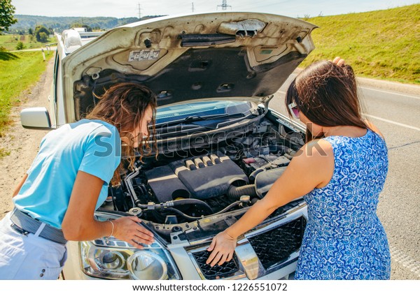 two women at\
roadside need help with broken\
car