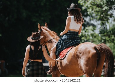 Two women are seen horseback riding, enjoying a sunny day in the outdoors while wearing cowboy hats. The scene portrays relaxation and adventure in nature. - Powered by Shutterstock