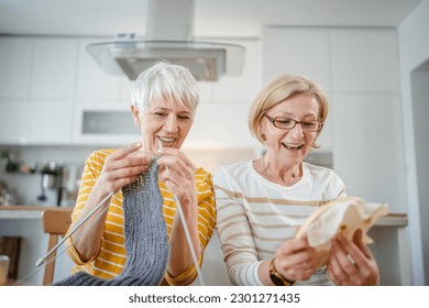 two women senior mature caucasian friends or mother and daughter or sisters knitting and embroidery during leisure time at home needlework concept bright photo happy and relaxed enjoy free time