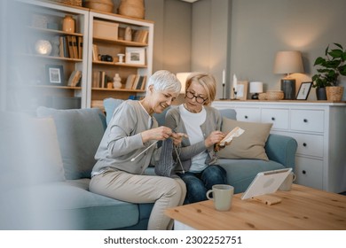 two women senior mature caucasian friends or mother and daughter or sisters knitting and embroidery during leisure time at home needlework concept happy and relaxed enjoy free time - Powered by Shutterstock