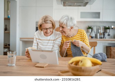 two women senior mature caucasian friends or mother and daughter or sisters knitting and embroidery during leisure time at home needlework concept bright photo happy and relaxed enjoy free time
