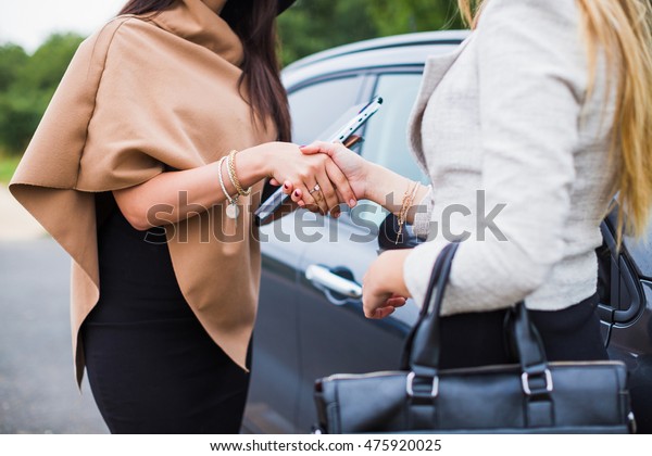 Two women shake hands at the machine.\
Conclusion of the agreement. Selling\
car