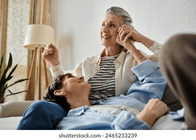 Two women share a loving moment seated on a couch together. - Powered by Shutterstock