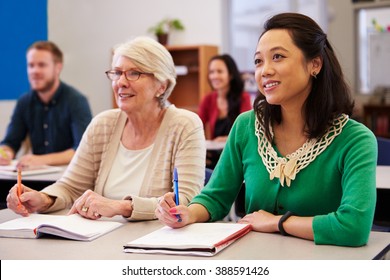 Two women sharing a desk at an adult education class look up