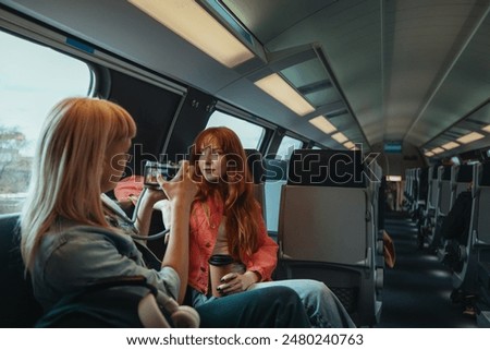 Two women sharing a digital camera, capturing moments of their journey to a music festival, together on a train