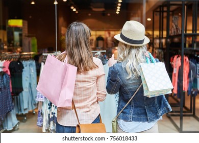 Two women shopping as customers in front of a retail boutique