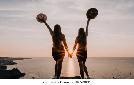 Two Women Silhouetted Against a Sunset on a Clifftop - Powered by Shutterstock