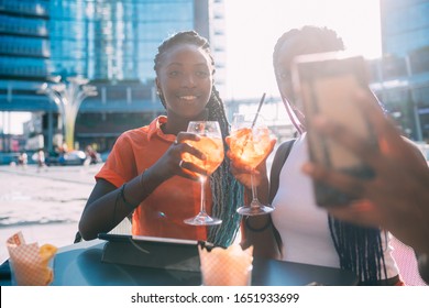 Two Women Sisters Sitting Outdoor Bar Having Happy Hour Using Smart Phone Taking Selfie - Conviviality, Technology, Relaxing Concept