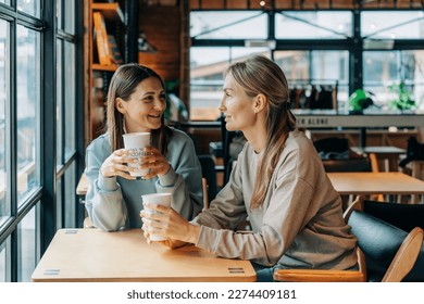 Photo of Two women sitting in a coffee house talking and drinking coffee.