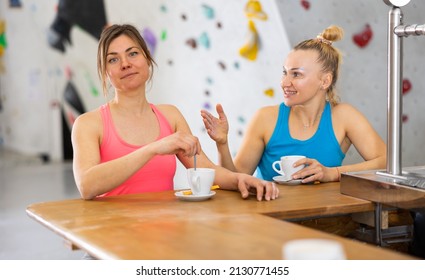 Two Women Standing At Bar Counter In Bouldering Gym, Drinking Tea And Chatting During Break.