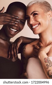 Two women standing together and having fun. Multi-ethnic female models with short hairstyle smiling in studio.