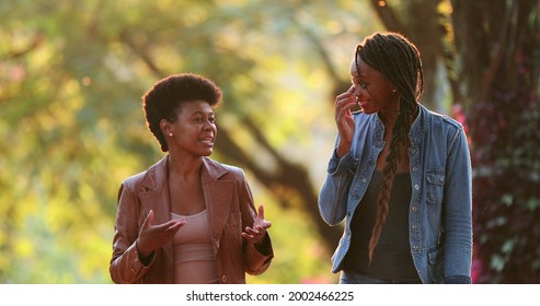 Two Women Talking Outside While Walking. African Friends In Conversation Outdoors