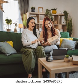 two women teenage friends or sisters receive presents in box open read card happy smile in front of digital tablet at home online video call - Powered by Shutterstock