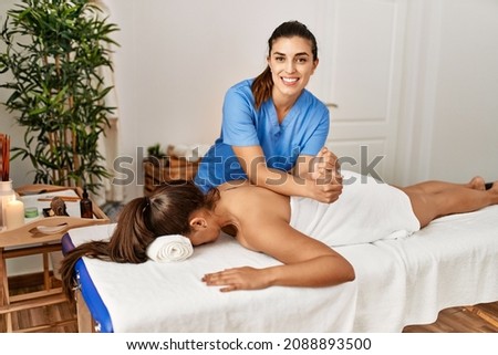 Two women therapist and patient having massage session massaging back at beauty center