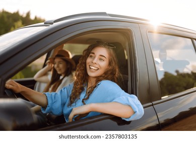 Two women travelers travel by car, have fun. Beautiful female friends in the car enjoy a car trip together. Travel, tourism.