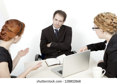 Two Women Try To Explain A Business Proposal To An Unimpressed Man. Business Meeting Concept