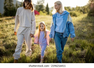 Two Women Walk With Little Girl, Happily Spending Summer Time On Nature. Homosexual Family With A Kid Travel In Mountains