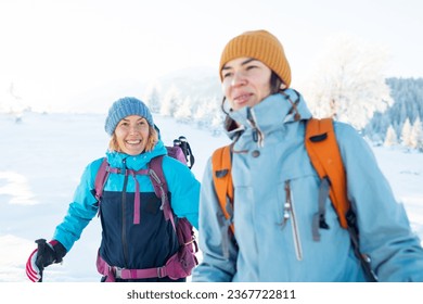 Two women walk in the snow, winter trekking, two people in the mountains in winter, hiking equipment