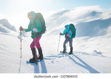 Two Women Walk In Snowshoes In The Snow, Winter Trekking, Two People In The Mountains In Winter, Hiking Equipment