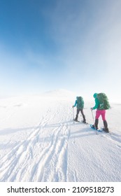 Two Women Walk In Snowshoes In The Snow, Winter Trekking, Two People In The Mountains In Winter, Hiking Equipment