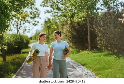 Two women walking with yoga mats in park, friends, fitness, sunny day - Powered by Shutterstock