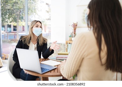 Two Women Wearing Face Masks Have A Meeting Inside An Office. On